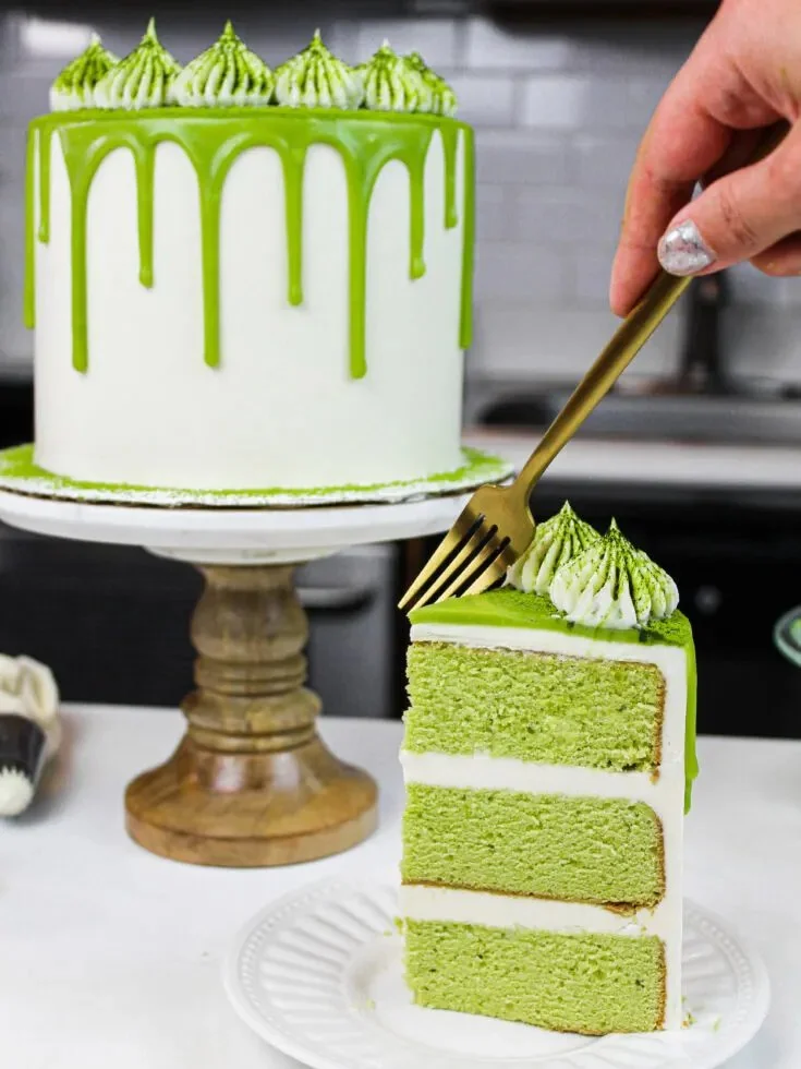Delicious green matcha cake slice with frosting and decorative matcha powder