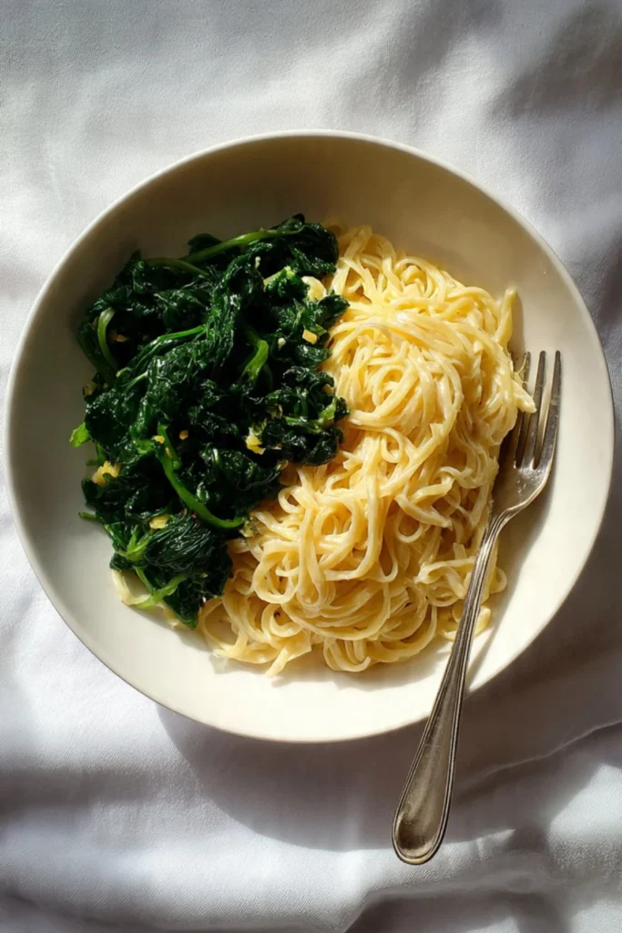 Plate of buttered noodles mixed with vibrant greens, garnished to perfection