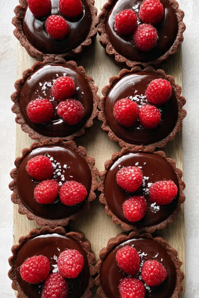 Delicious Chocolate Raspberry Tartlets topped with fresh raspberries and chocolate drizzle