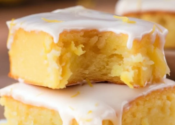 Delicious lemon brownies topped with a sweet glaze on a white plate