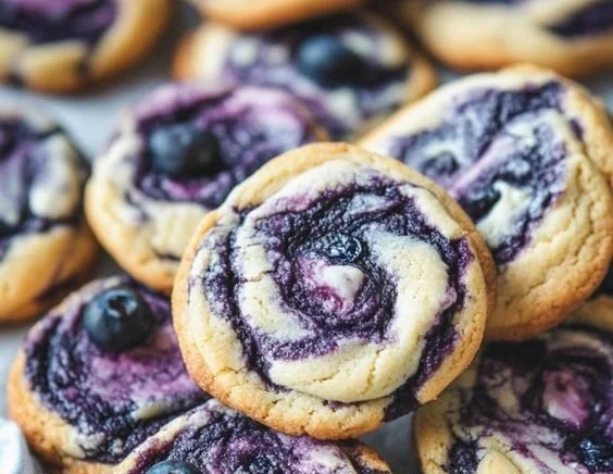 Blueberry cheesecake cookies on a plate with fresh blueberries and mint leaves.