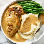 Delicious creamy garlic chicken plated with herbs and garlic cloves