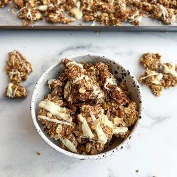Bowl of easy vegan cinnamon roll granola clusters with nuts and spices