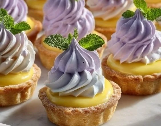 Mini lemon tarts topped with lilac meringue in a decorative presentation