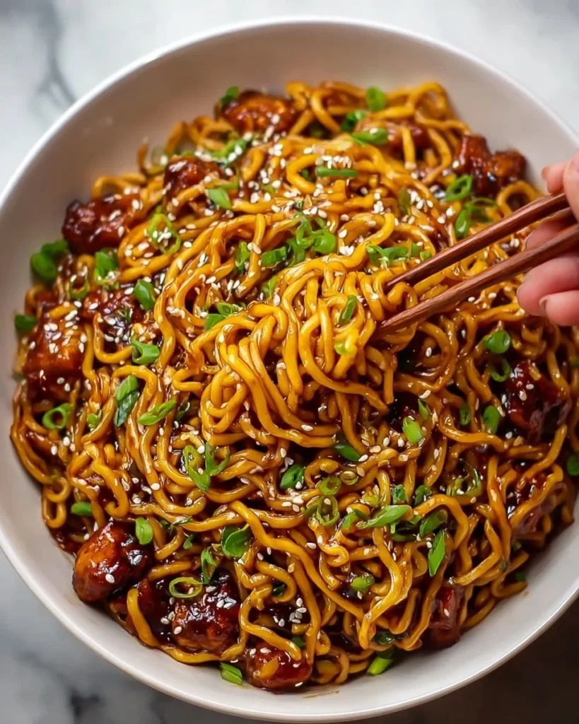 Sticky Garlic Chicken Noodles in a bowl with fresh herbs