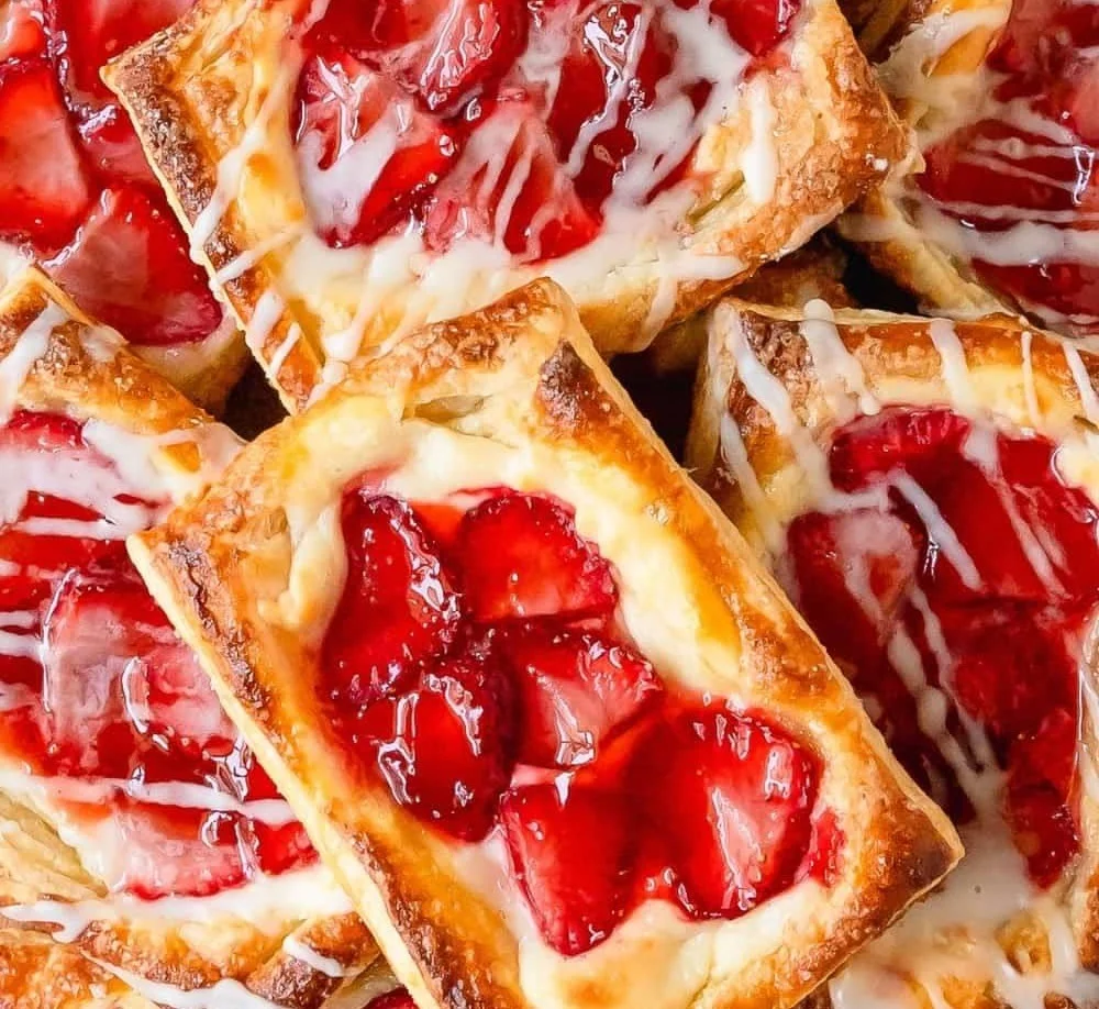 Freshly baked Strawberry Danish pastry topped with strawberries and icing.