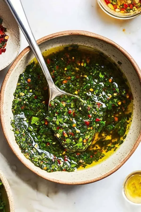 A bowl of traditional chimichurri sauce with fresh herbs and olive oil.