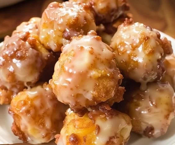 Freshly made Apple Fritter Bites on a plate, drizzled with icing.