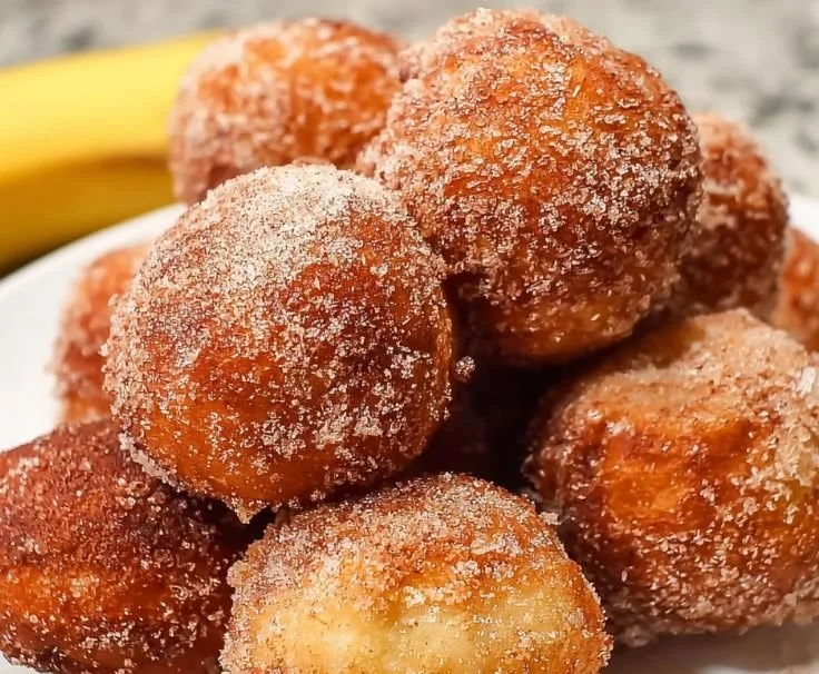 Freshly baked banana donut holes dusted with powdered sugar