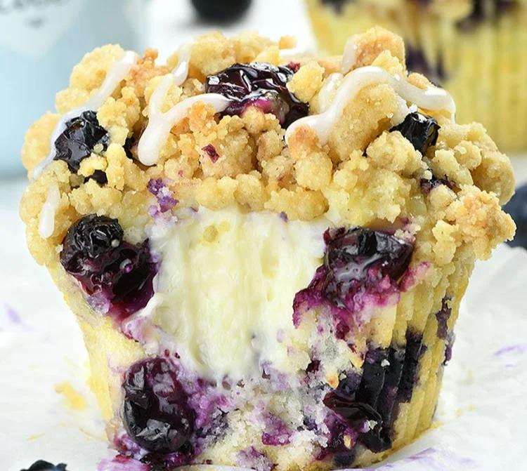 Blueberry cream cheese muffins fresh out of the oven, topped with blueberries.