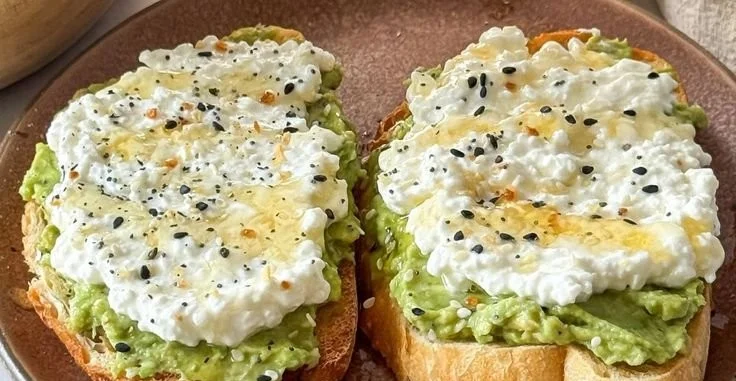 Plate of cottage cheese avocado toast topped with herbs and cherry tomatoes