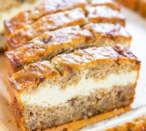 Sliced cream cheese-filled banana bread on a wooden table