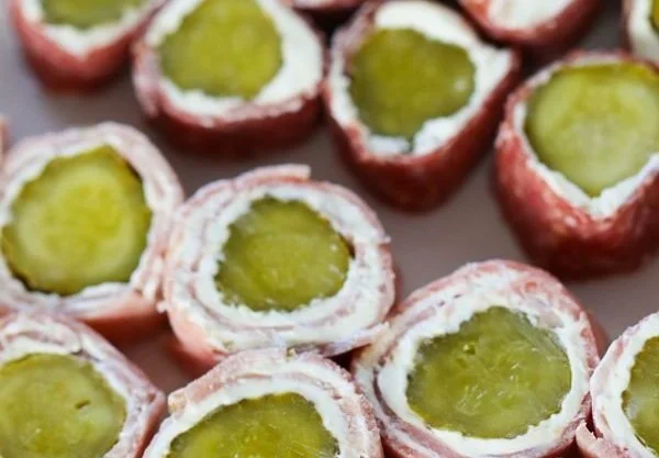 Cream cheese ham and pickle roll-ups ready to serve on a platter