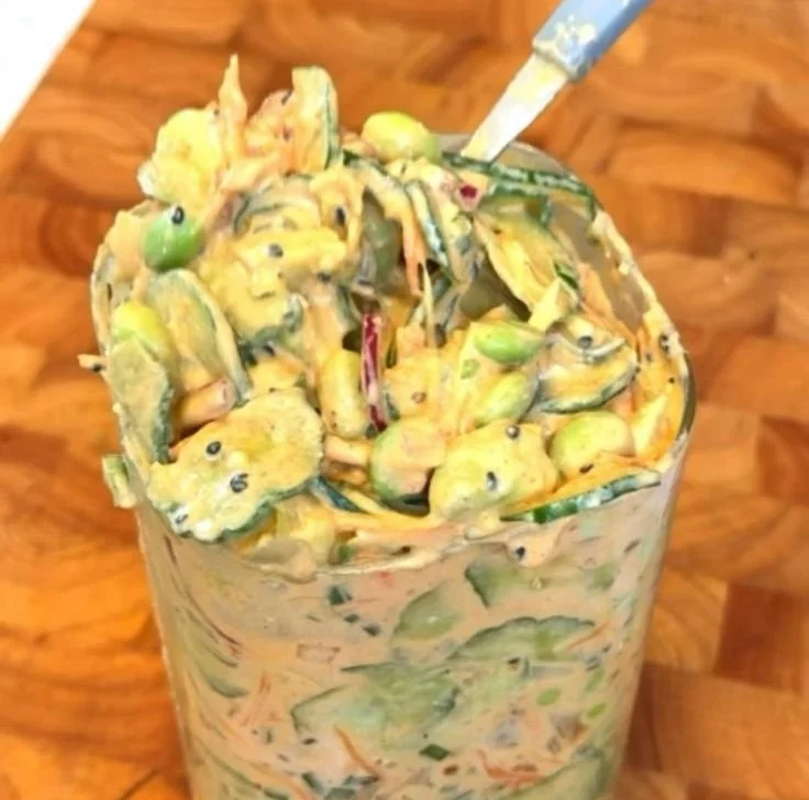 Creamy cucumber salad with Asian flavors, garnished with sesame seeds and herbs.