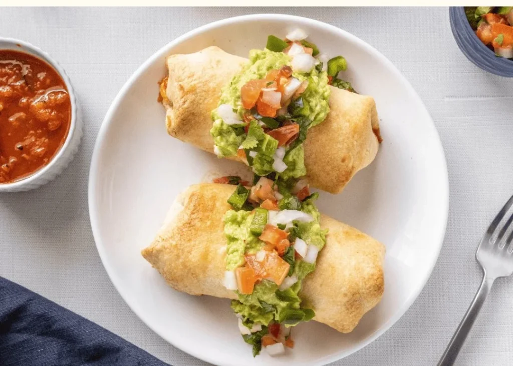 Crispy chicken burritos topped with guacamole and pico de gallo