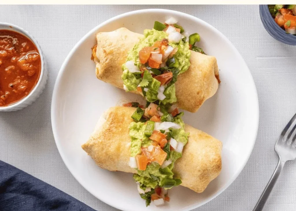 Delicious crispy chicken burritos topped with guacamole and pico de gallo