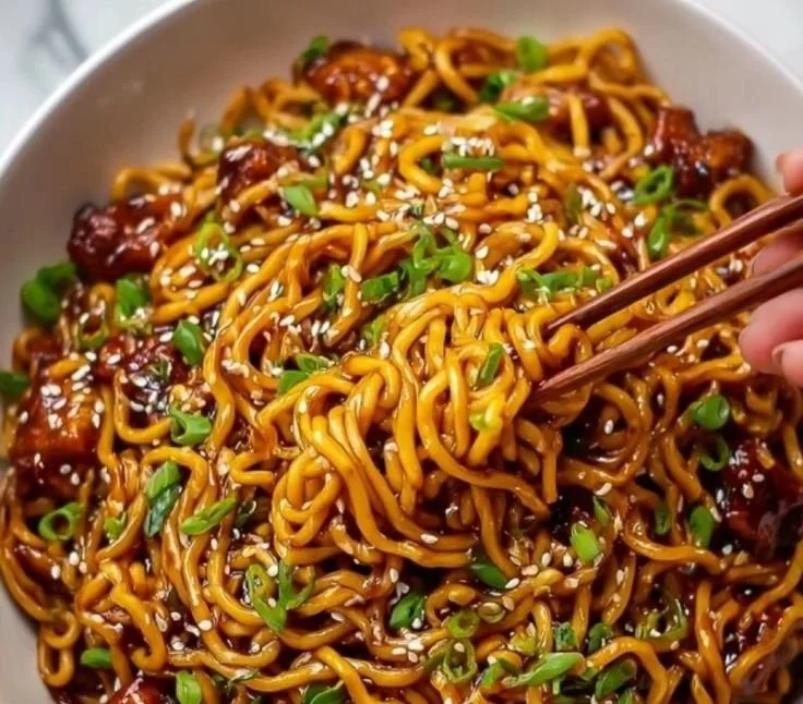 Plate of Garlic Chicken Noodles with Sticky Sauce, garnished with herbs.