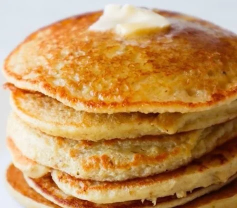 Healthy oatmeal apple pancakes stacked on a plate with fresh apples