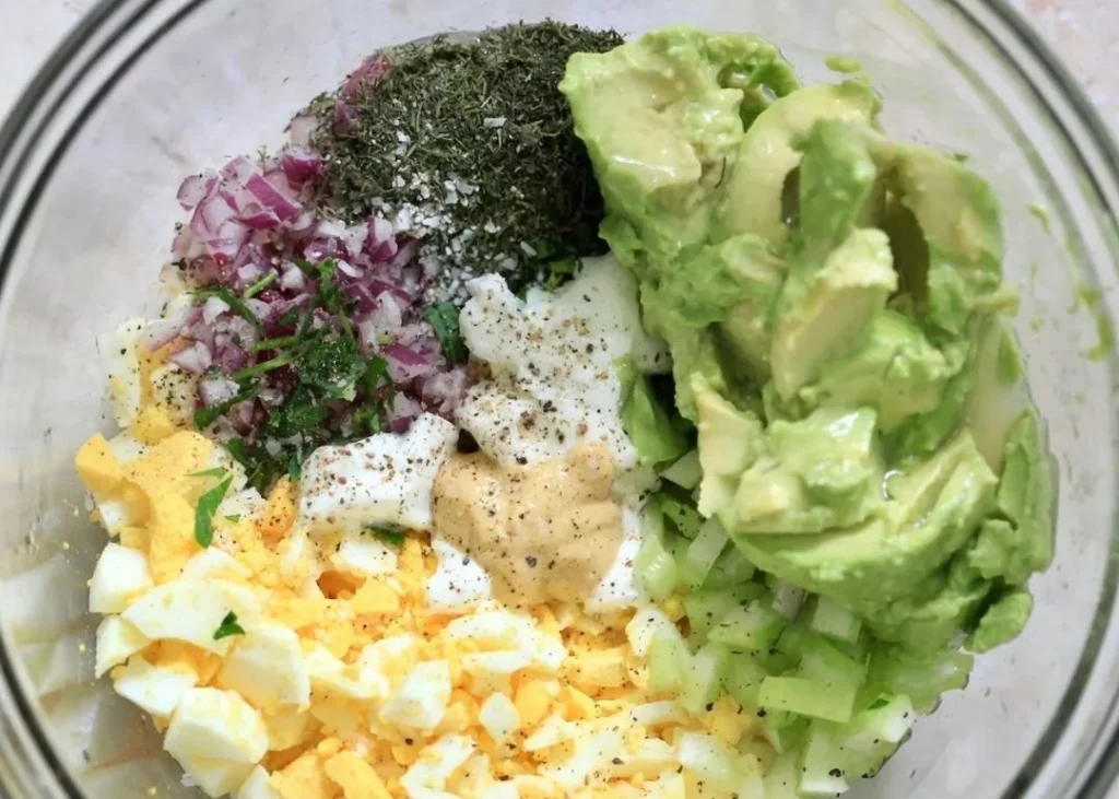 High protein avocado egg salad served in a bowl with fresh ingredients.
