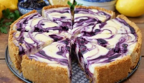 Slice of lemon blueberry cheesecake garnished with blueberries and lemon zest.