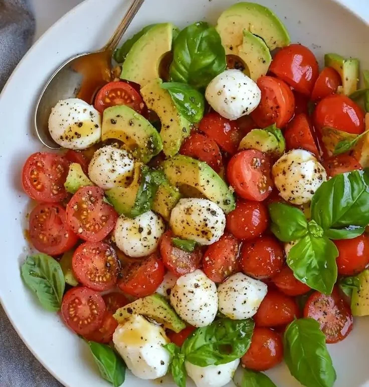 Light avocado caprese salad with fresh mozzarella, tomatoes, and basil