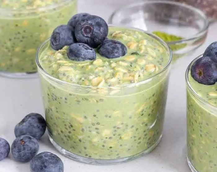 A bowl of matcha overnight oats topped with berries and nuts.