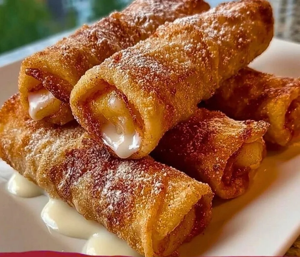 Peach cobbler egg rolls served on a plate with a scoop of vanilla ice cream.