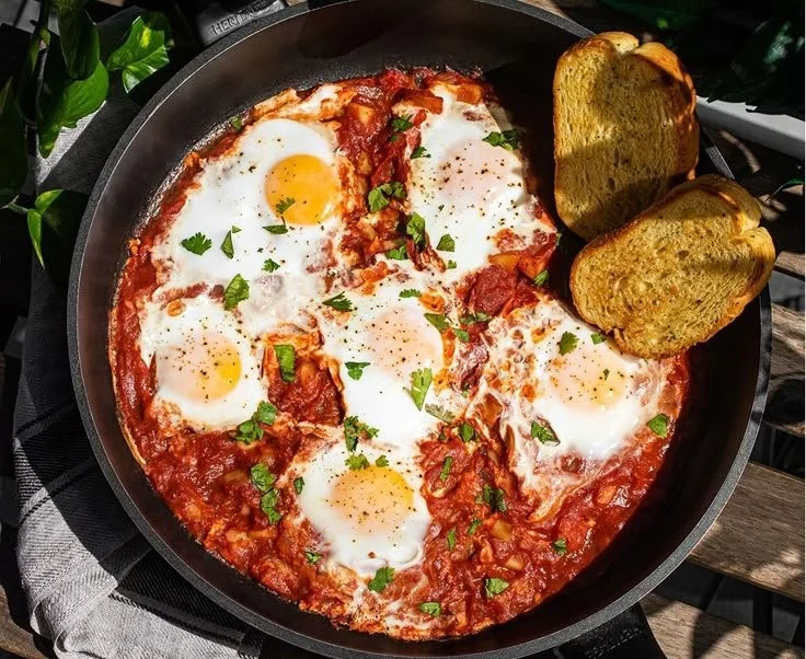 Delicious shakshuka with poached eggs in spicy tomato sauce served in a skillet.