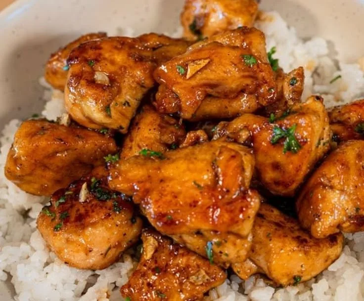 Delicious honey garlic chicken bites served with rice on a plate.