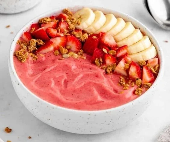 Strawberry banana smoothie bowl topped with fresh fruit and granola