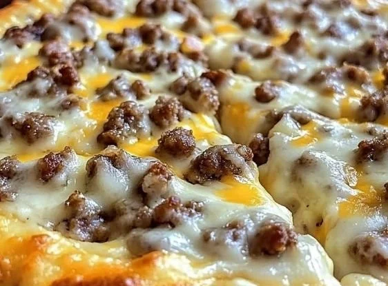 Breakfast pizza topped with biscuits and sausage gravy on a plate.