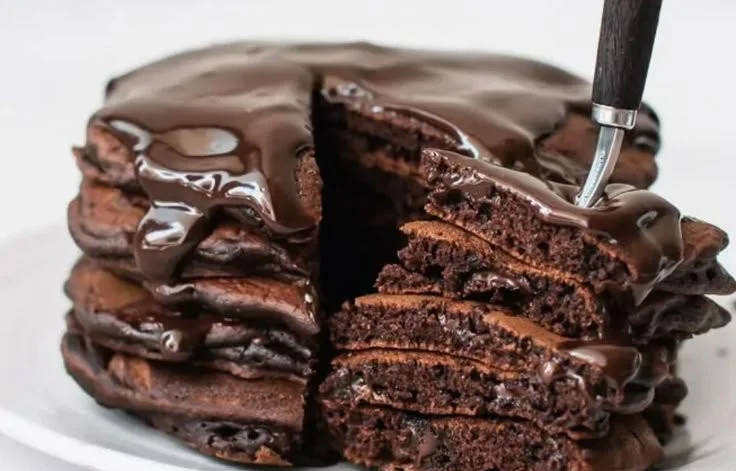 Fluffy and delicious cloud-soft chocolate pancakes served with syrup and berries.