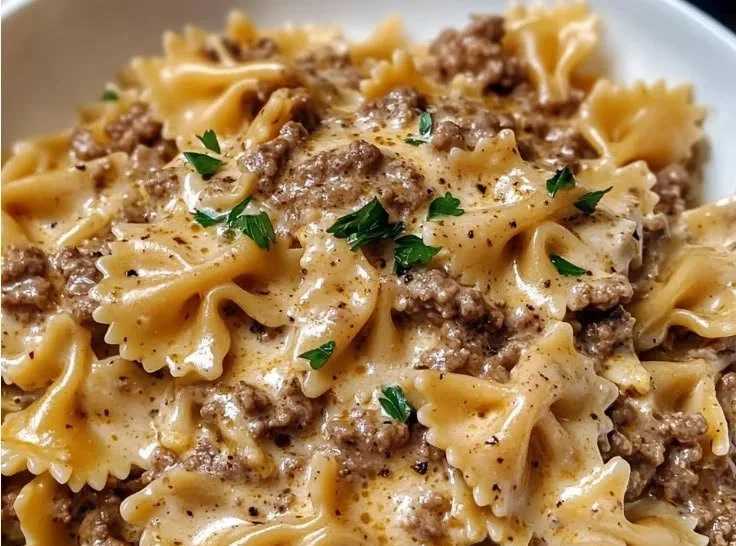 Creamy beef pasta served in a bowl garnished with basil and parmesan cheese.