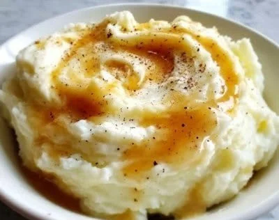 Creamy mashed cauliflower in a white bowl with herbs and seasoning