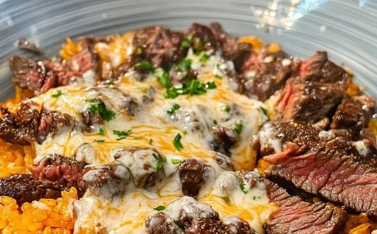 Creamy queso rice served with juicy steak strips on a plate