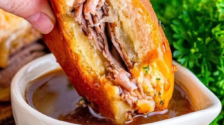French Dip Sliders with au jus for dipping on a wooden serving tray