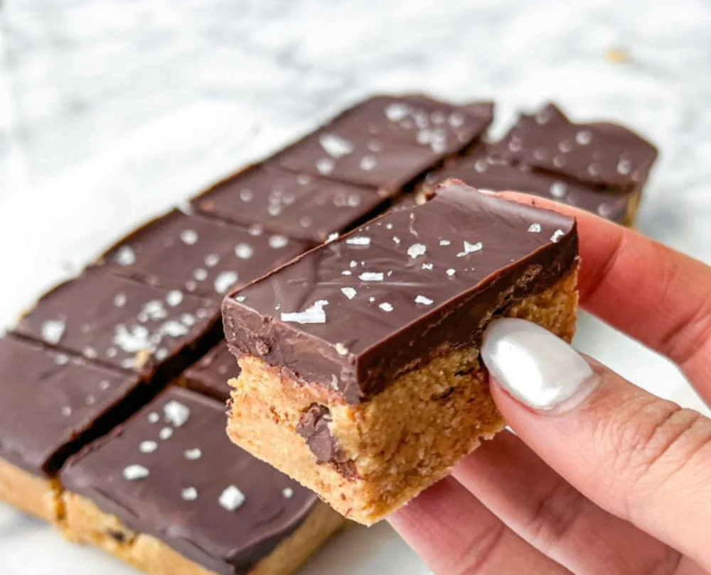 Healthy no-bake cookie dough bars on a white plate with scattered chocolate chips.