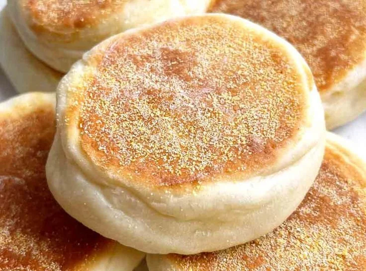 Homemade English muffins fresh out of the oven, golden brown and fluffy.