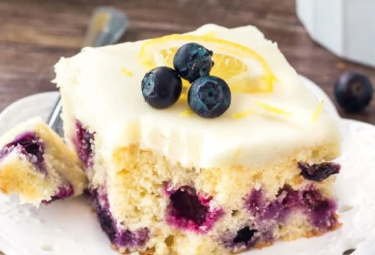 Freshly baked lemon blueberry cake topped with blueberries and lemon zest.