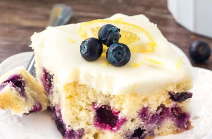 A delicious slice of Lemon Blueberry Cake topped with fresh blueberries and lemon zest.