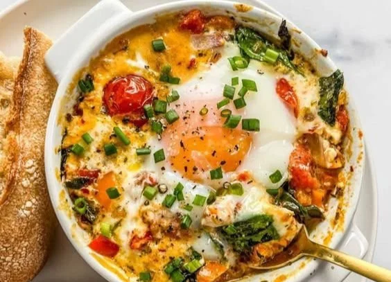 Oven-baked feta eggs with tomatoes and spinach served in a baking dish.
