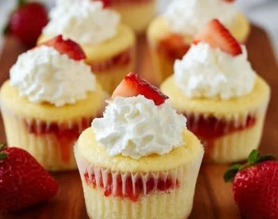 Strawberry shortcake cupcakes topped with fresh strawberries and whipped cream