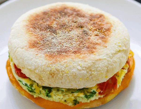 Tomato spinach egg sandwich with fresh ingredients on a plate
