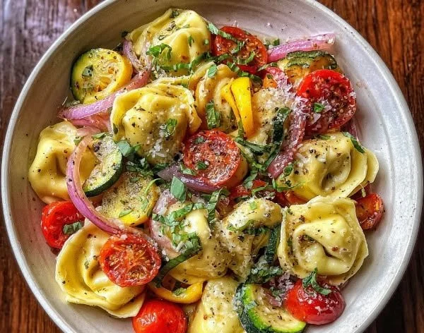 Bowl of tortellini with summer vegetables, showcasing vibrant colors and fresh ingredients.
