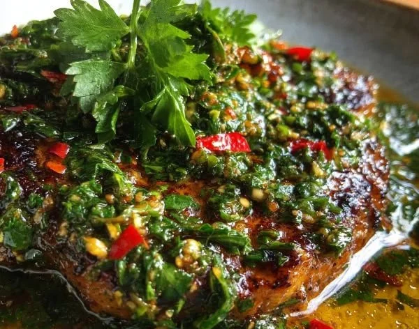 Homemade zesty Argentinian chimichurri sauce in a bowl with fresh herbs.