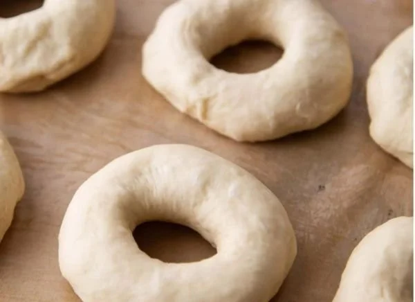 Freshly baked bagels on a wooden board with toppings