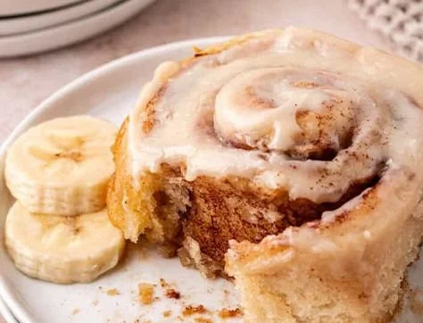 Banana bread cinnamon rolls with cream cheese frosting on a plate