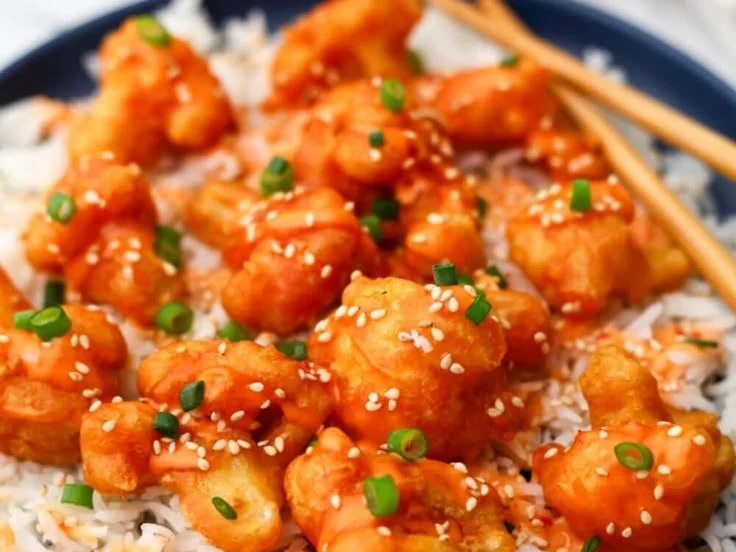 Crispy Bang Bang Cauliflower served on a plate with creamy sauce and garnishes