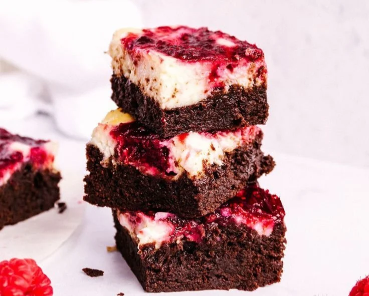 Delicious raspberry cheesecake brownies topped with fresh raspberries and creamy layer.