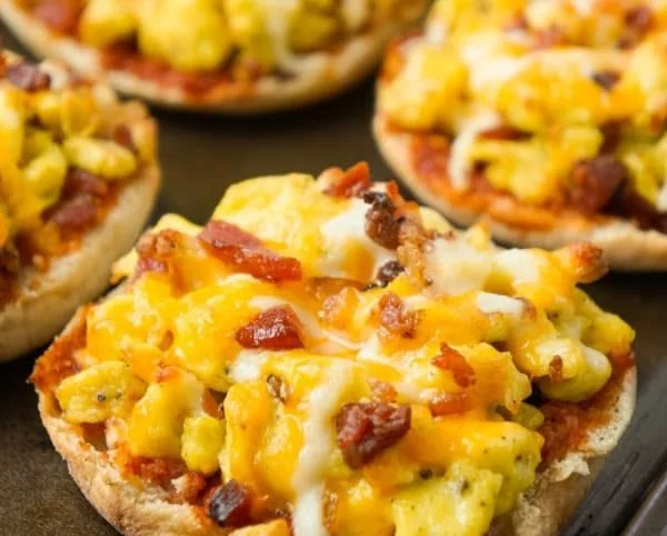 Breakfast pizzas on toasted English muffins topped with eggs and cheese